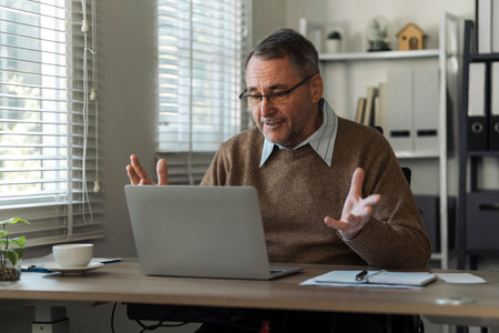 Retired senior man talking to taxman online about annual tax. Tax concept.