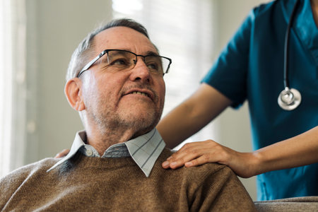 Caregiver encourages and comforts elderly man in nursing home care and confide in caregiverの写真素材