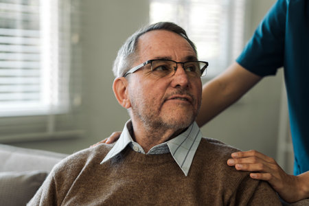 Caregiver encourages and comforts elderly man in nursing home care and confide in caregiverの写真素材