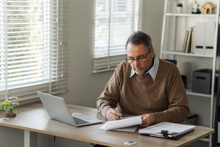 Retired old man is calculating stress about annual tax, debt, arrears in the house. Tax concept.の写真素材