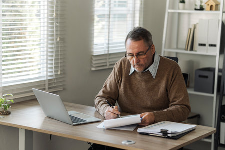 Retired old man is calculating stress about annual tax, debt, arrears in the house. Tax concept.の写真素材