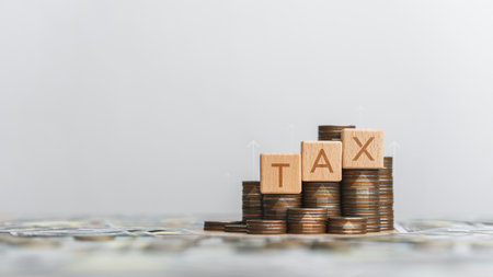 Stack of silver coins with wooden blocks word Tax. Income tax filing concept and filing taxes to pay tax documents online to the government. Annual tax planning concept. Finance and tax system.の写真素材