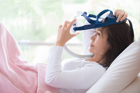 Woman lay in bed wearing CPAP mask ,sleep apnea therapy. Happy and healthy woman,sleep apnea,wearing...