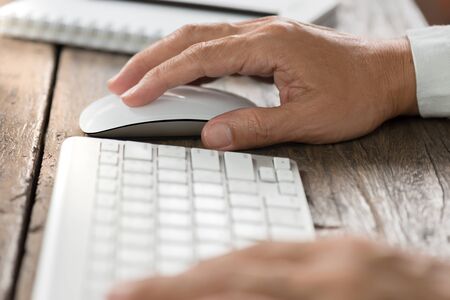 Never easy like tthis before. Man hands using wireless mouse and keyboard on old wooden table.