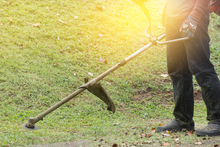 Close up of man holding grass trimmer. Worker mowing lawn with garden trimmer rotating left and right.の写真素材
