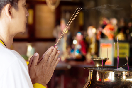 Man praying for new year ,lighting incense to Buddha.
Burning joss stick and oil palm candle at chinese shrine for making merit in chinese new year festival. 
May his life be blessed with health  and happiness all through.の写真素材