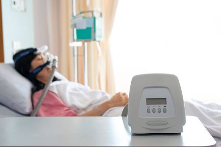 Cpap machine is treating senior patient woman wearing Cpap mask sleeping smoothly without snoring in hospital room.Obstructive sleep apnea therapy.の写真素材