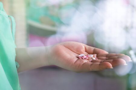 Close up of woman hand holding lot of pills with bokeh and blur background wearing hospital green clothes.Pills on woman left hand.の写真素材