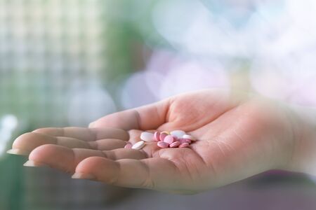 Close up of woman hand holding lot of pills with bokeh and blur background.Pills on woman hand.の写真素材