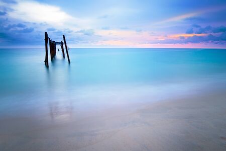 Long exposure shot of old wooden bridge at Khao pilai beach at sunset .Decay bridge reflection in smooth sea surface.の写真素材