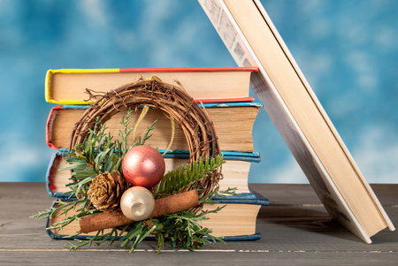 group of books on a wooden surface with a Christmas wreath folded verticallyの写真素材