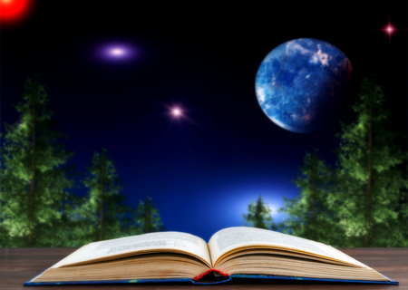 a book against the backdrop of a landscape with coniferous trees and the night sky with starsの写真素材