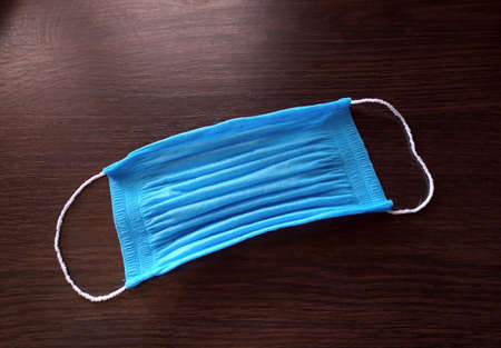 Blue medical mask on a wooden surface. Viral disease concept