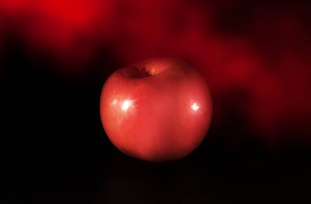 Red apple on black  with red smoke