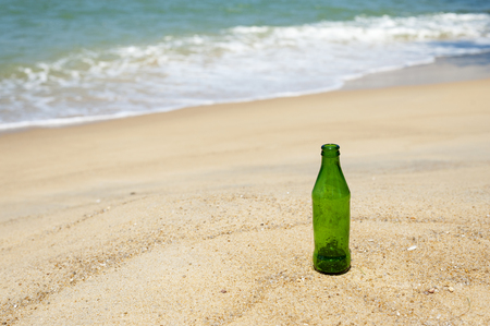 Green bottle on the sand.の写真素材