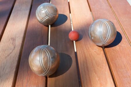 Metallic petanque balls and a small red jack on wood tableの写真素材