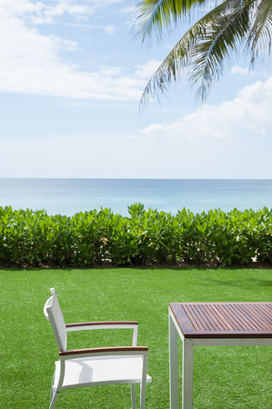 Chairs and wood table in the grass. By the seaの写真素材