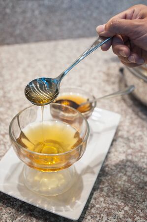 Syrup pouring and dripping out of a spoonの写真素材