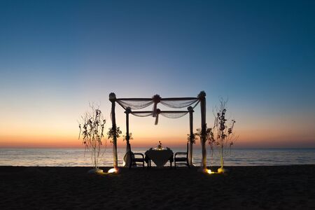 Romantic dinner setting on the beach at sunsetの写真素材