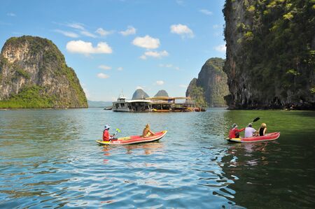 Tourists kayaking through limestone cliffs in Phang-nga Bay of Thailandの写真素材