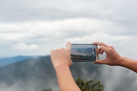 man photographed mountains morning fog in the smartphone.の写真素材