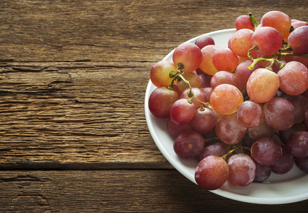 Fresh grapes in a plate white on dark wood boardの写真素材
