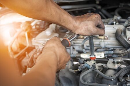 Hands of mechanic working in auto repair shop with sunlight