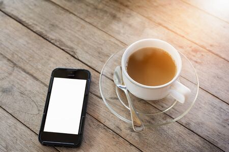 coffee cup and cell phone on wooden table with
Morning sunの写真素材