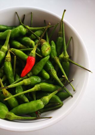 Red and Green chili in bowl in white backgroundの写真素材