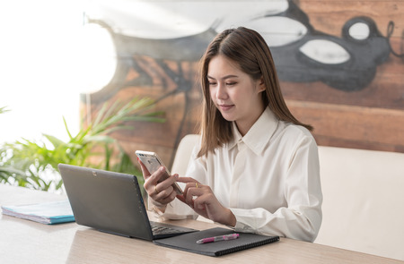 Modern business woman or successful working on smart phone and laptop computer at coffee shop...