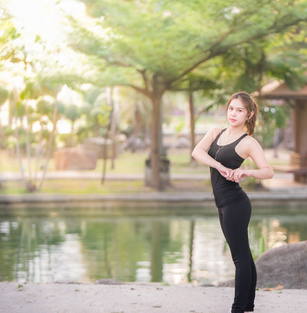 Young female stretching before fitness training session at the park. Healthy young woman warming up outdoors. She is stretching her arms and looking awayの写真素材