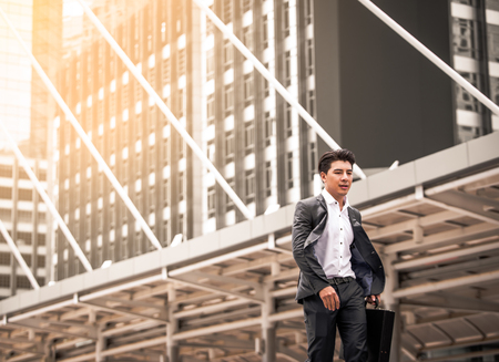 Happy Asian businessman walking along the streetの写真素材