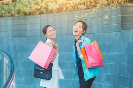 sale, consumerism and people concept - happy young women looking into shopping bags at shop in city.の写真素材