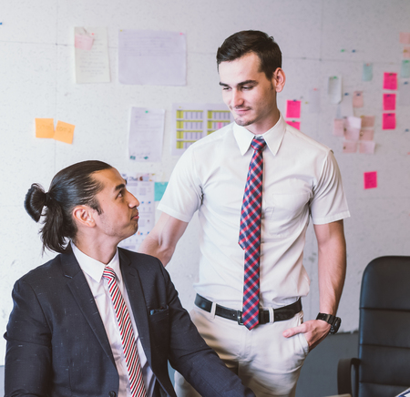 Caucasian business executive praising subordinate by giving a pat on the shoulder with eye contact.の写真素材