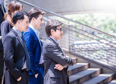 Successful business team is smiling while standing with crossed arms outdoors urban city