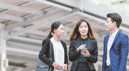 Group of Asian business colleagues using mobile phone's outside the office.の写真素材