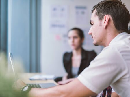 Business, technology, internet and networking concept. Young male businessman sitting at a desk in the office.の写真素材