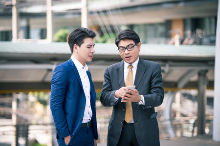 Asian middle business people use and play with their smart phone.show to colleaguesの写真素材