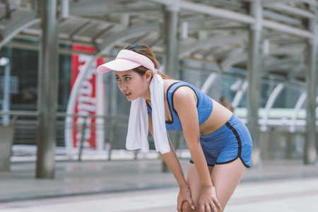 Asian sport woman is tried and rest after running in cityの写真素材