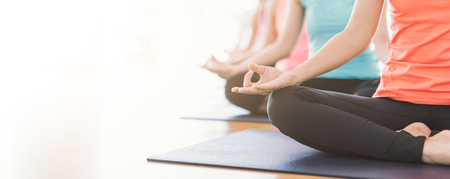 Attractive young Asian woman group exercising and sitting in yoga lotus position in yoga classes Breath control with copy spaceの写真素材