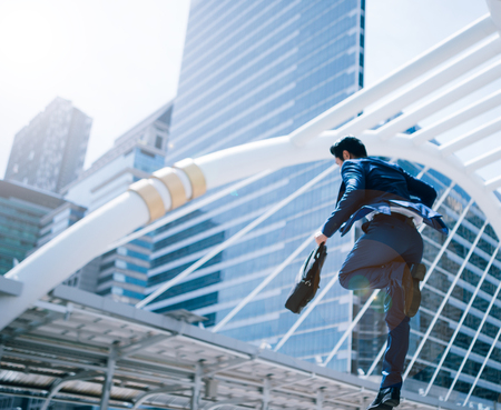 Jumping running business man in front of buildingsの写真素材