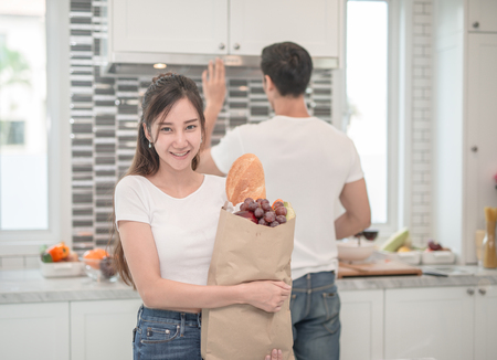 Young couple in the kitchen , woman with a bag of groceries shoppingの写真素材
