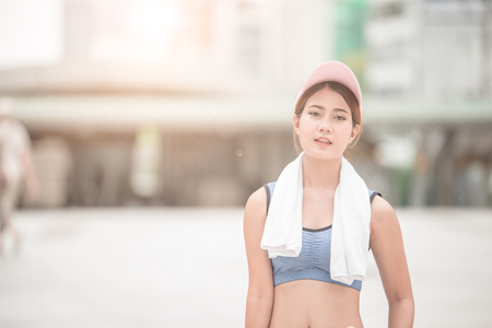 Asian sport woman with towel jogging and running in city centerの写真素材