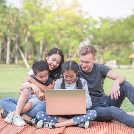 Modern family using laptop while resting in parkの写真素材