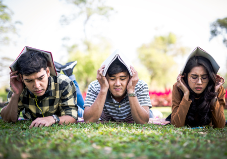 Teenager students outside protecting there heads by  books  exam stress hard conceptの写真素材
