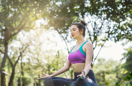 Yoga in the park healthy exercise. woman do lotus yoga poseの写真素材