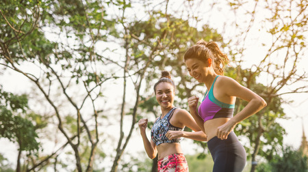 Two athletic woman running outdoors. Action and healthy lifestyle concept.Jogging run in parkの写真素材