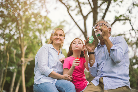 happy family in green nature park on summer ,grandfather blow soap bubbles along with grandchildrenの写真素材