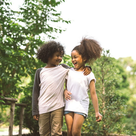 Children Friendship Togetherness Smiling Happiness Concept.Cute african american little boy and girl hug each other in summer sunny dayの写真素材