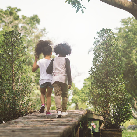 Children Friendship Togetherness Concept. African american little boy and girl hug each other in summer sunny day back viewの写真素材